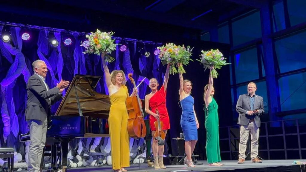 Gruppe Salut Salon beim Schlussapplaus mit Blumen in den Händen.